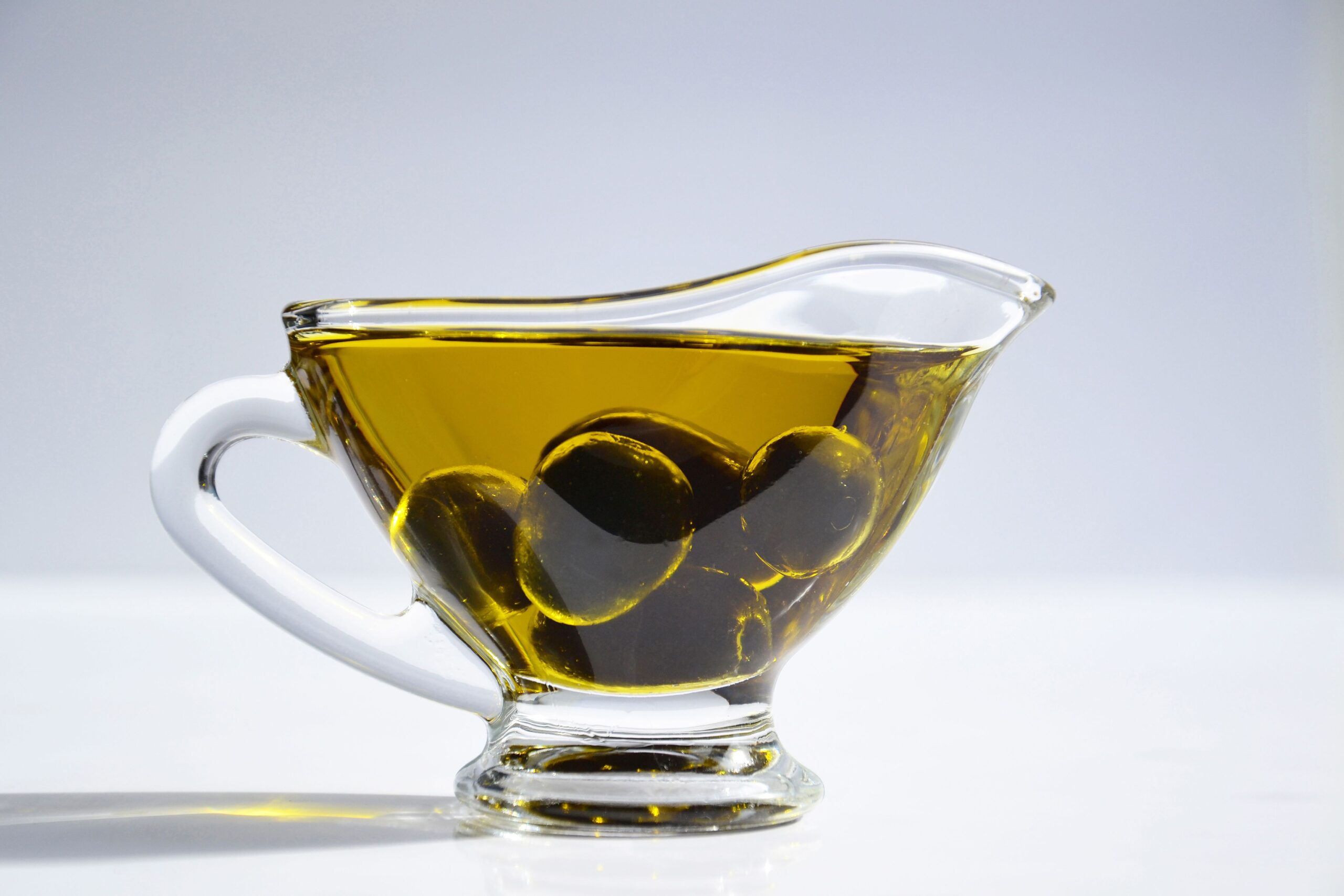 pexels photo 1022385 1022385 High-resolution image of a glass cup filled with olive oil and olives, ideal for culinary themes.
