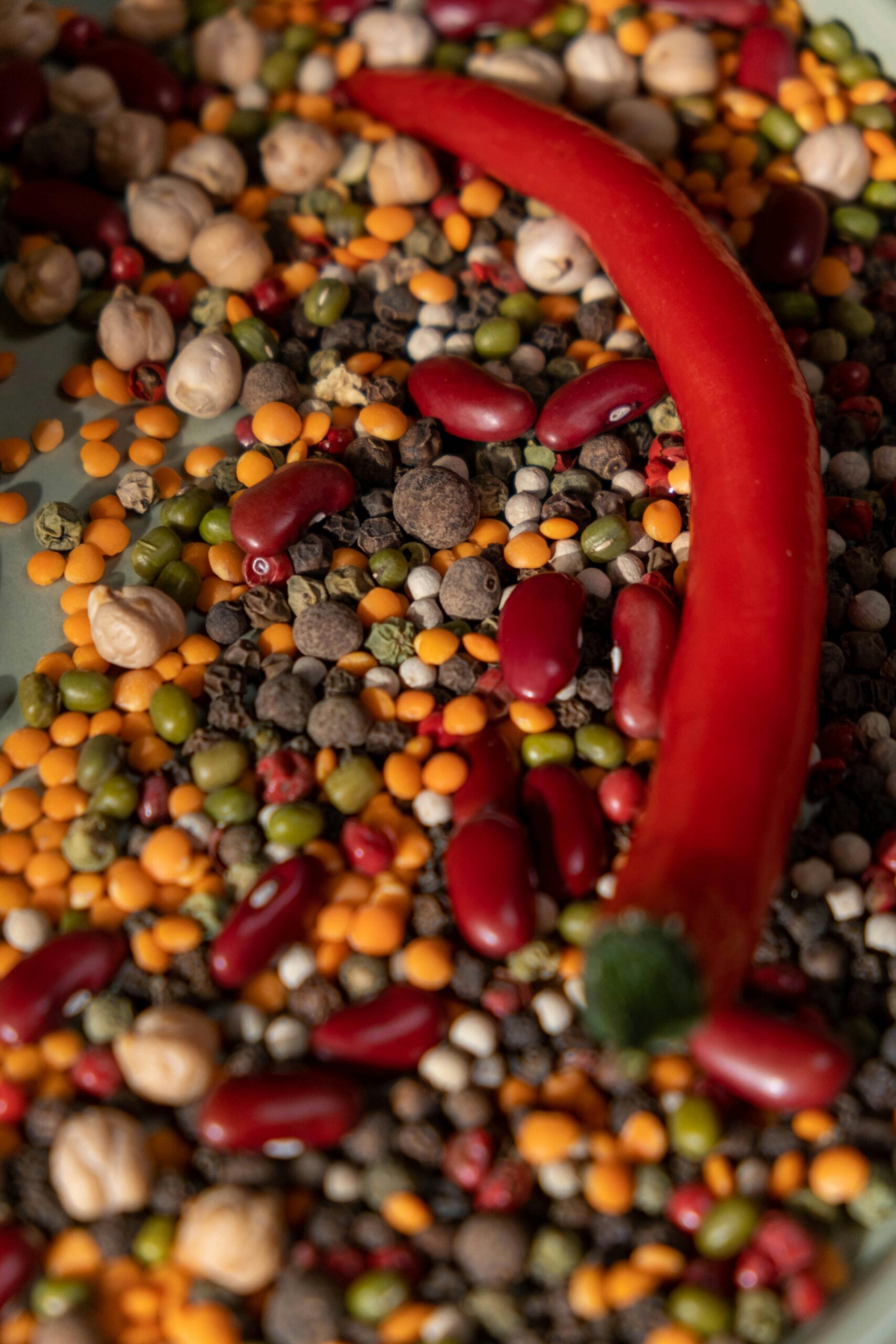 pexels photo 6805783 6805783 Colorful close-up of raw spices and legumes with a vibrant red chili pepper.